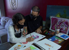 Marina e o pai, André, desenham e criam juntos na sala de casa