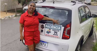 A professora aposentada Mirtes Macedo, recém habilitada, pede "paciência". O aviso está na placa colocada do lado de fora do carro. - Foto: TV Anhaguera/G1